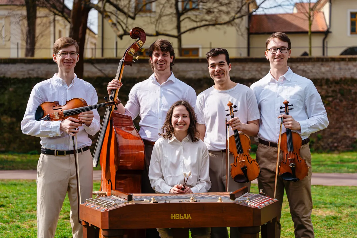 Muzikanti hrají kolem cimbálu při společném vystoupení