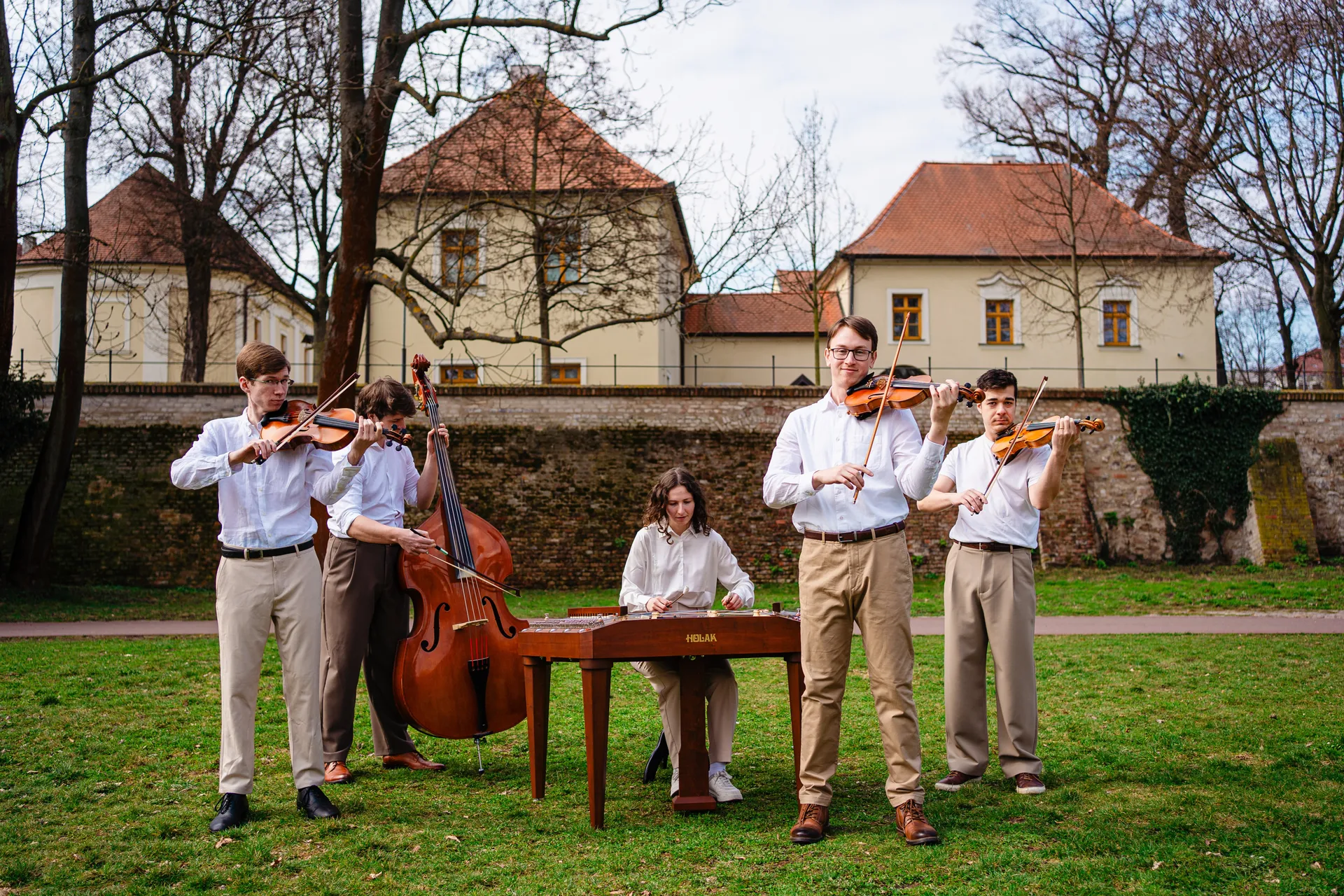 Kapela Zornička při vystoupení na trávě před historickou budovou